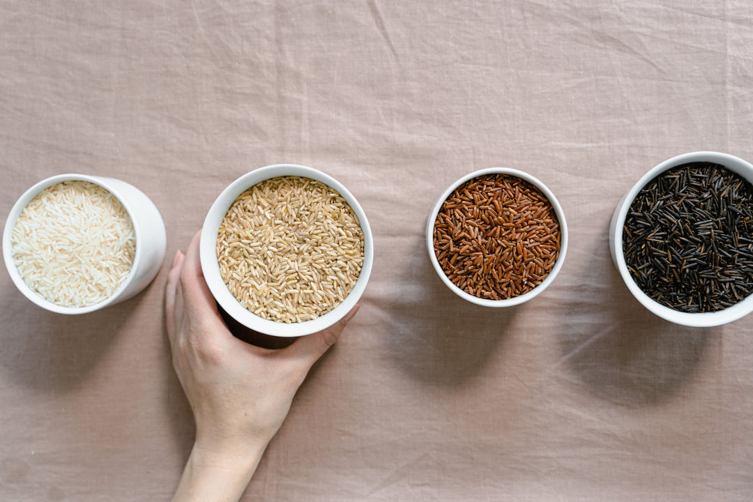White jasmine rice, brown rice, red rice and wild rice in bowls compared side by side