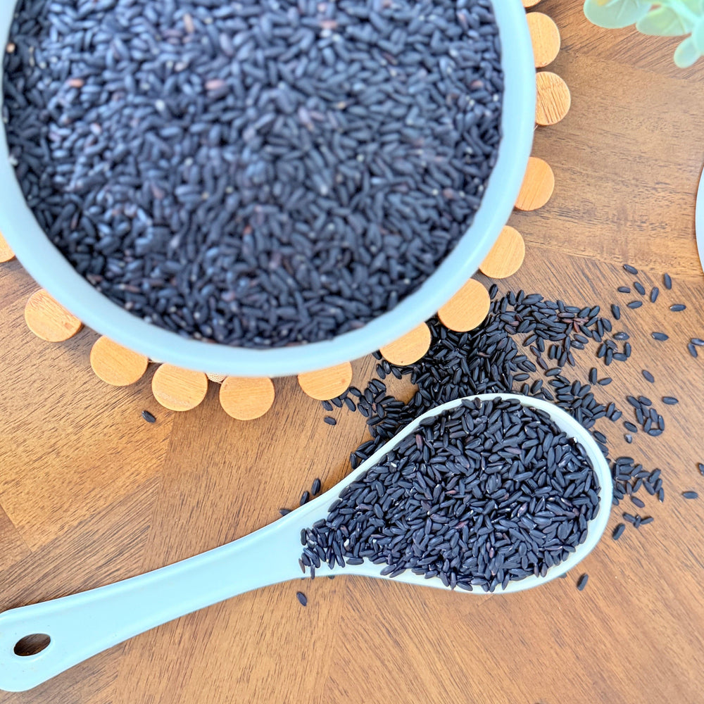 A bowl of uncooked organic black rice, rich in natural pigments, perfect for adding color, texture, and nutrition to a variety of dishes."