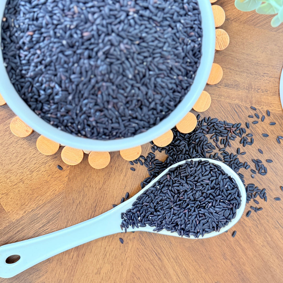 A bowl of uncooked organic black rice, rich in natural pigments, perfect for adding color, texture, and nutrition to a variety of dishes."
