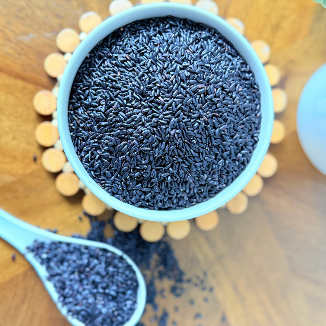 High-quality organic black rice photographed on a rustic wooden table, featuring glossy grains and a rich hue, suitable for salads, bowls, and side dishes